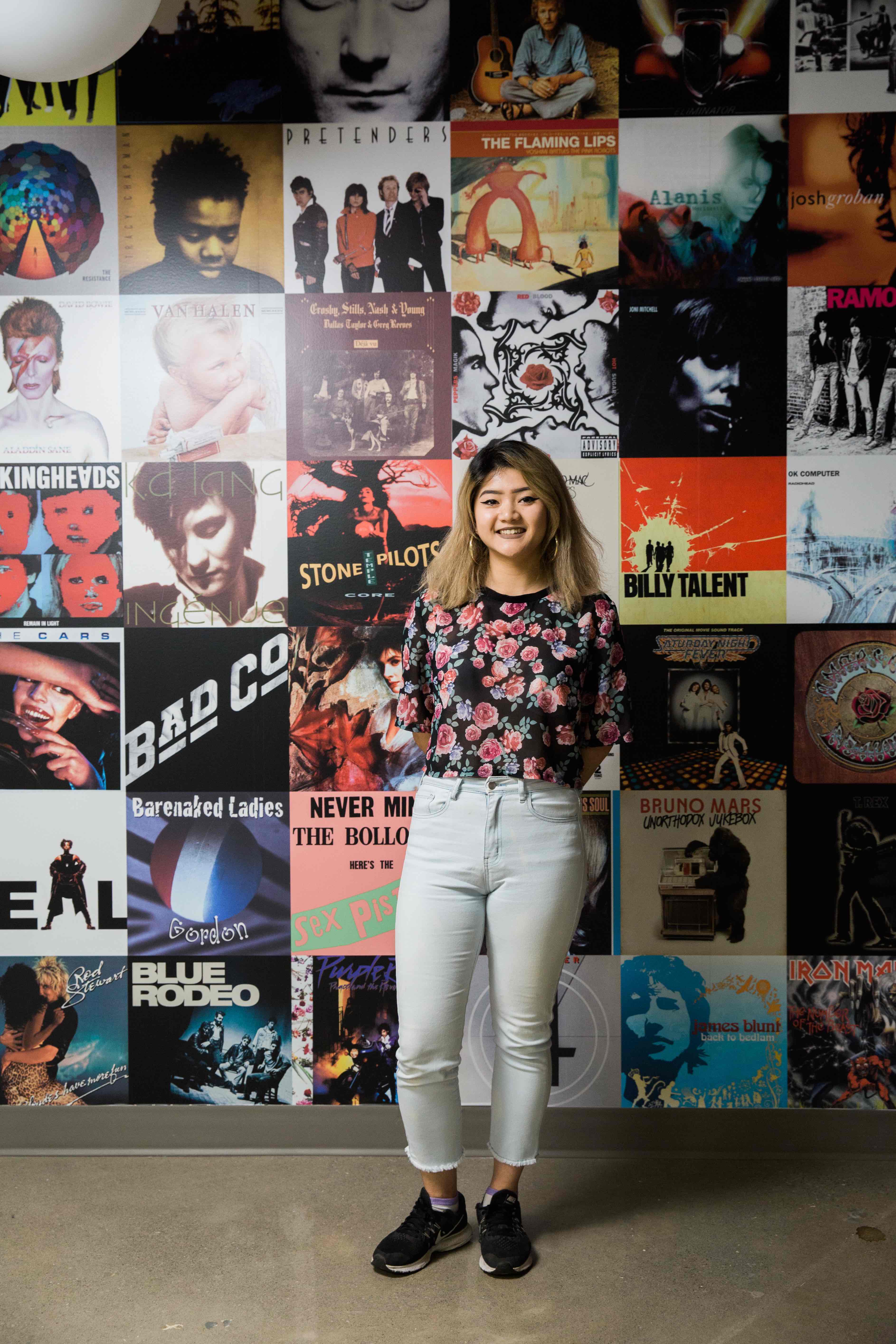 The image displayed shows a student standing in front of a wall of record covers.